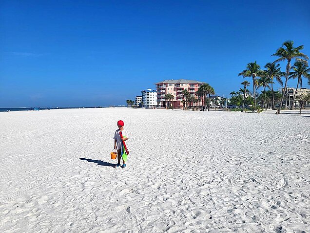 Palm trees, wide white sandy beach, and beautiful ocean in Fort Myers Beach